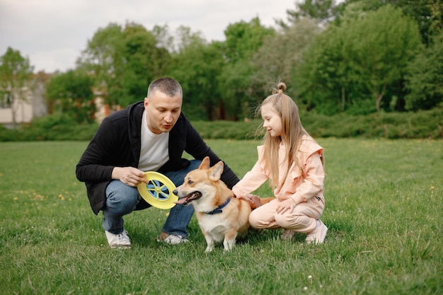 Pai sua filha e seu cachorro corgi brincando juntos em um parque de primavera
