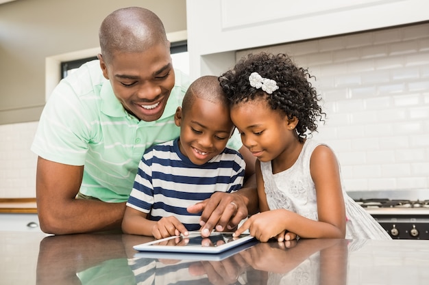 Pai usando tableta com seus filhos na cozinha