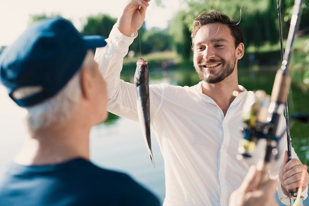 Pai velho com filho de barba pesca no rio.