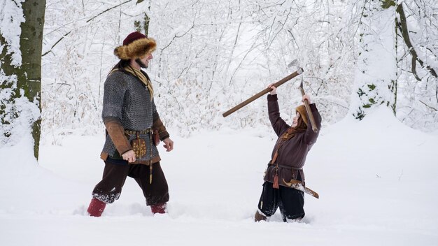 Pai viking com seu filho na floresta de inverno Eles se vestiram com roupas medievais