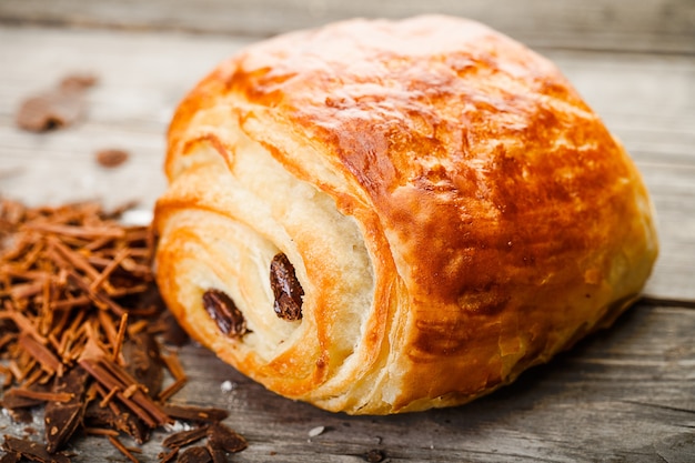 Pain au Chocolat mit Schokolade, die auf altem Holztisch liegt