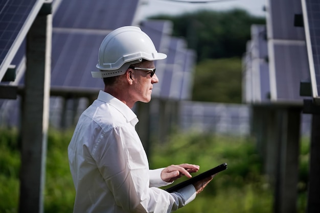 Painéis solares de fazenda solar com engenheiros usando um tablet para verificar a operação do sistema energia alternativa para conservação de energia mundial conceito de módulo fotovoltaico para geração de energia limpa