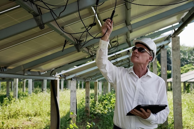 Painéis solares de fazenda solar com engenheiros usando um tablet para verificar a operação do sistema Energia alternativa para conservação de energia mundial Conceito de módulo fotovoltaico para geração de energia limpa