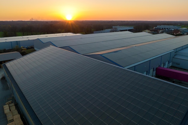 Painéis solares fotovoltaicos azuis montados no telhado do edifício para produzir eletricidade ecológica limpa ao pôr do sol Produção do conceito de energia renovável