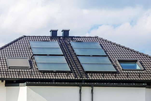 Painéis solares no telhado da casa Telhado de azulejos com janelas com persianas chaminés guardas de neve escadas