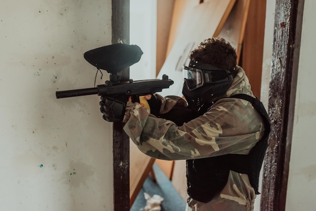 Paintball-Spieler mit Maske, der auf Gegner in einer Paintball-Arena zielt Selektiver Fokus Hochwertiges Foto