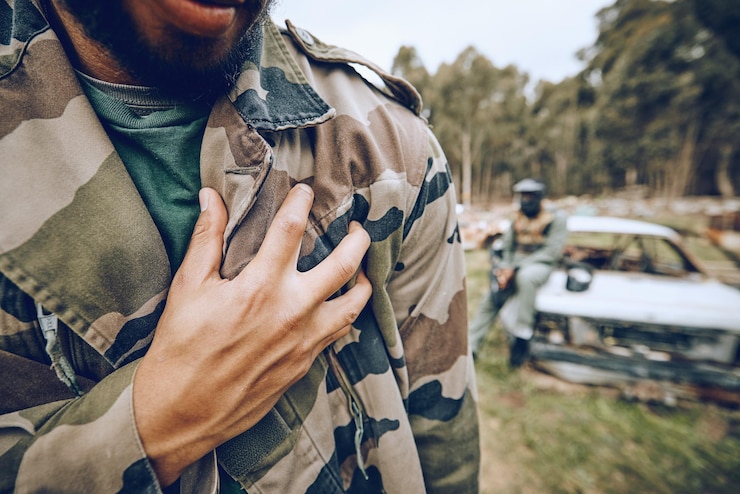 Foto paintball-tarnung und mann bei einem match-wettbewerb oder extremsporttraining auf einem schlachtfeld fitness-hand und männlicher athlet oder soldat mit militärischem outfit für ein lustiges spiel oder training im freien