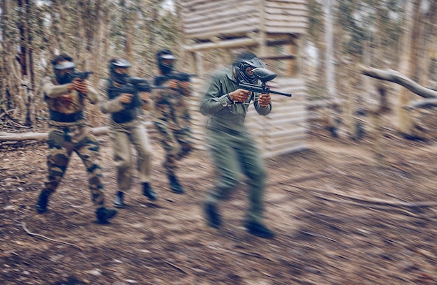 Paintball-Teamarbeit oder Männer, die in einem Schießspiel mit Geschwindigkeit oder schneller Aktion auf einem lustigen Schlachtfeld laufen. Mission konzentrieren sich auf Militär oder Menschen mit Waffen, um in einem Wettbewerb in der Natur oder im Wald zu überleben