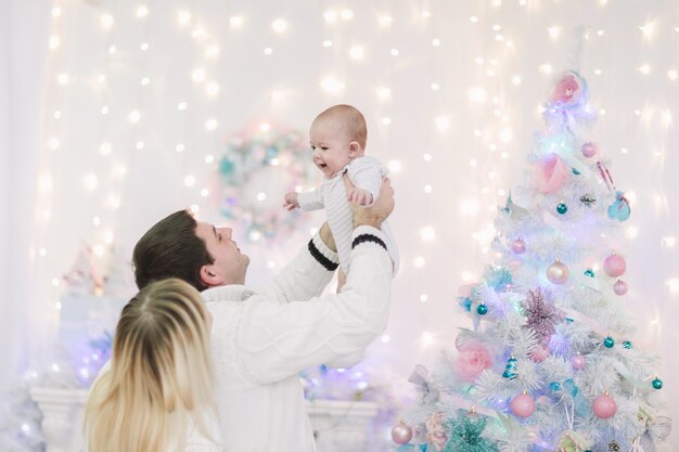 Pais amorosos brincam com seu bebê na véspera de Natal. o conceito de felicidade familiar