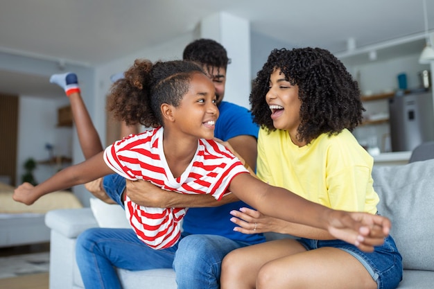 Pais amorosos diversos passam tempo com a filhinha adorável se divertem juntos em casa moderna sorrindo rindo de perto conceito de família multiétnica feliz