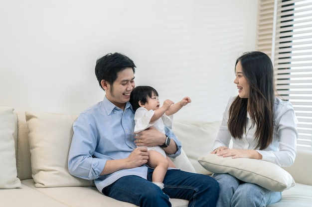 Pais asiáticos e uma criança brincando em casa. Conceito de família.