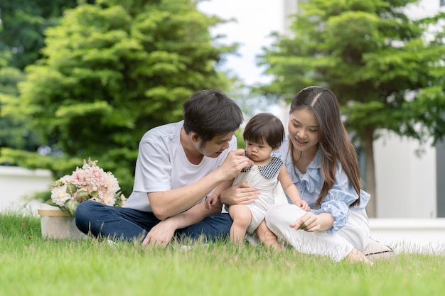 Pais asiáticos e uma criança brincando no jardim em casa. conceito de família.