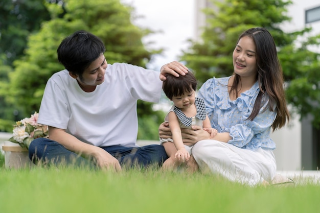 Pais asiáticos e uma criança brincando no jardim em casa. Conceito de família.