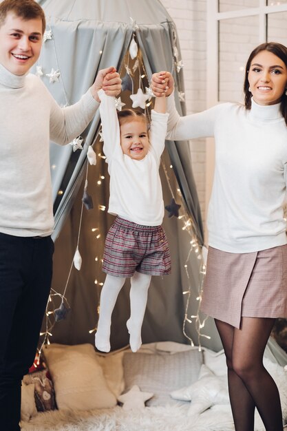 Pais brincando com a filha. Decorações de Natal.