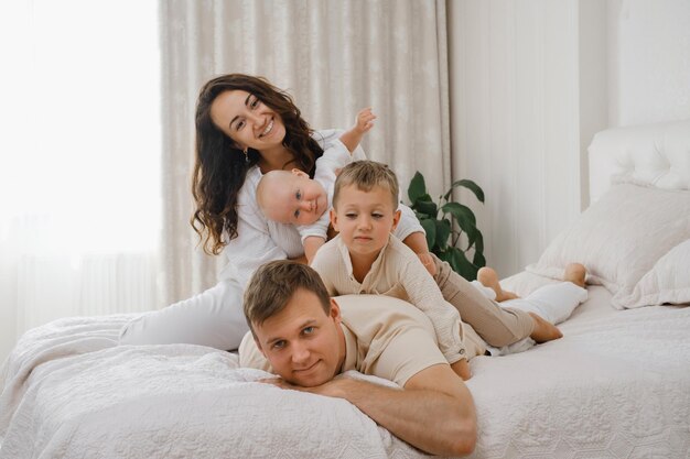 Pais brincando com crianças na cama em um aconchegante apartamento branco