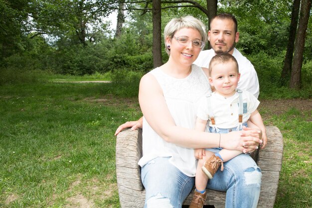 Pais com bebê no parque sentam-se no banco do jardim