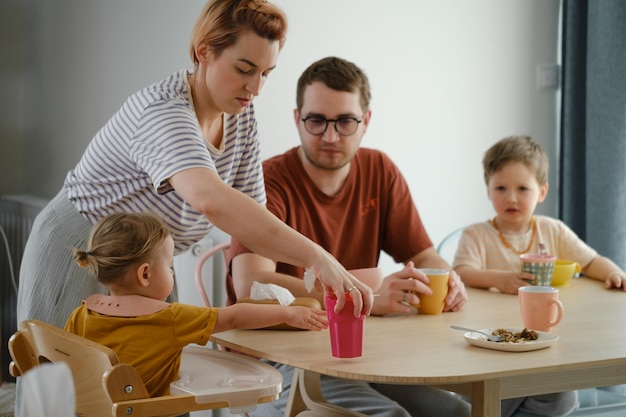 Pais com filhos tomando café da manhã à mesa em casa