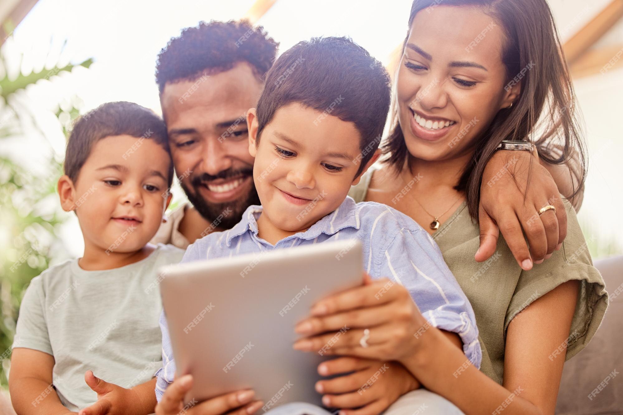 Mãe e filhos felizes com tablet digital assistem a vídeos engraçados,  filmes ou jogos no sofá