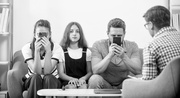 Foto pais de terapia familiar com garota conversam com assistente social, mãe e filha viciadas em telefone