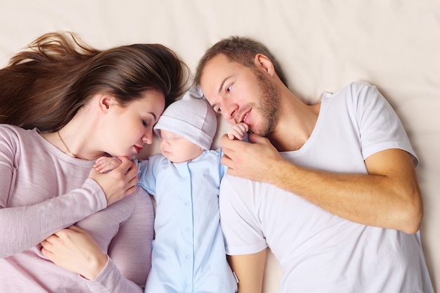 Pais deitados perto do bebê dormindo