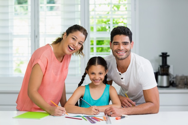 Pais e filha desenhando na cozinha em casa