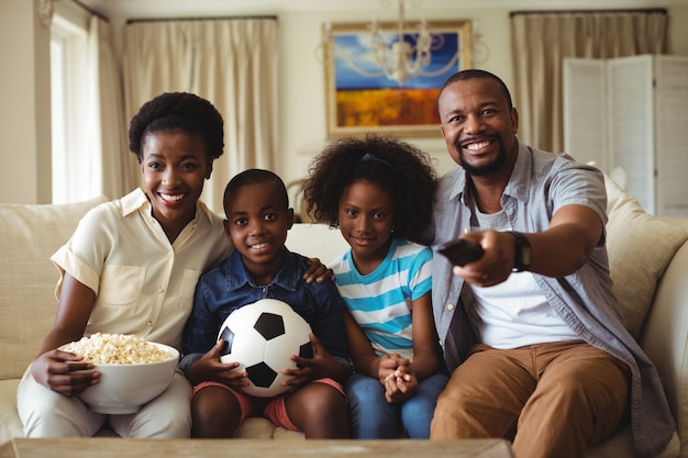 Pais e filhos assistindo televisão na sala de estar
