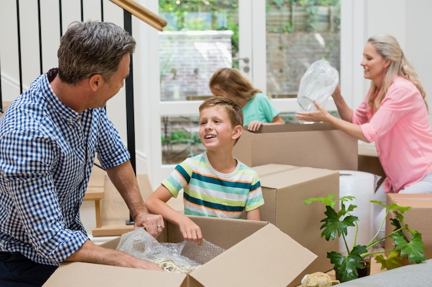 Pais e filhos desembalar caixas de papelão na sala de estar