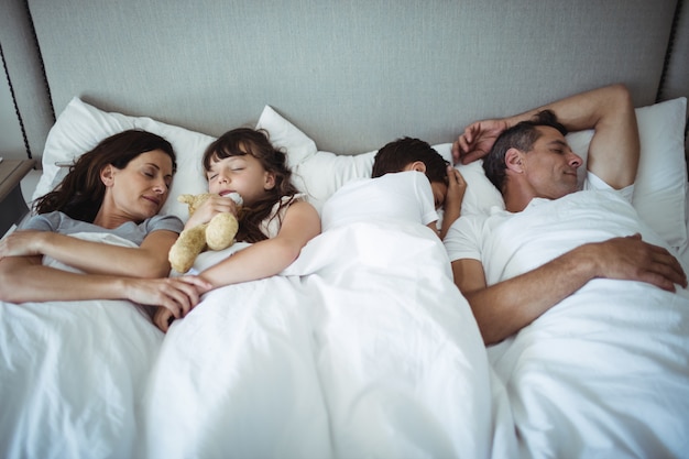 Pais e filhos dormindo na cama