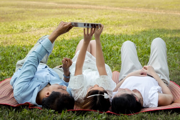 Pais e filhos estão jogando o tablet no tapete no parque.