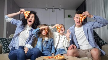 Foto pais e filhos gostam de comer pizza deliciosa juntos em casa