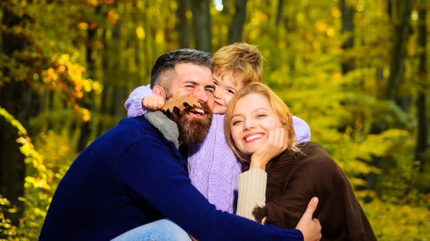 Pais e filhos juntos no parque dia ensolarado de outono. família feliz mãe e pai abraços filho pequeno