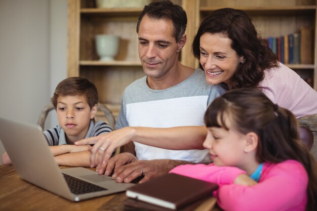 Pais e filhos usando o laptop na mesa na sala de estudo