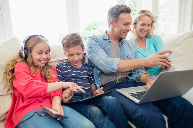 Pais e filhos usando tablet digital, telefones celulares e laptop