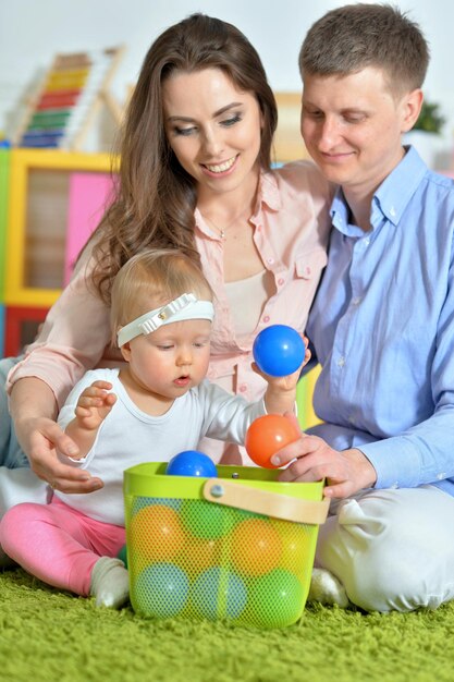 Foto pais felizes a brincar com a adorável filha na sala de jogos.