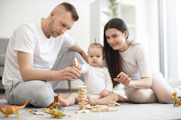 Pais felizes brincando com criança usando blocos de madeira