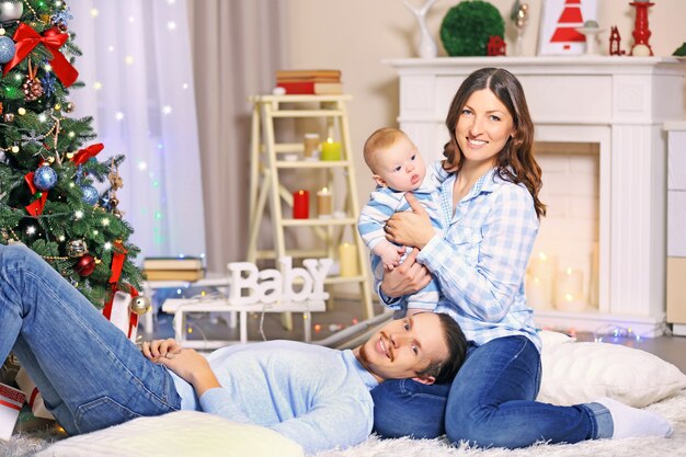 Pais felizes brincando com o bebê no chão da sala decorada de Natal