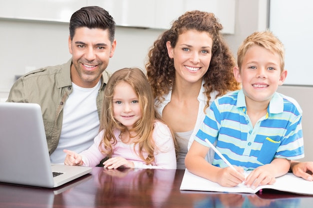 Pais felizes colorindo e usando laptop com seus filhos pequenos