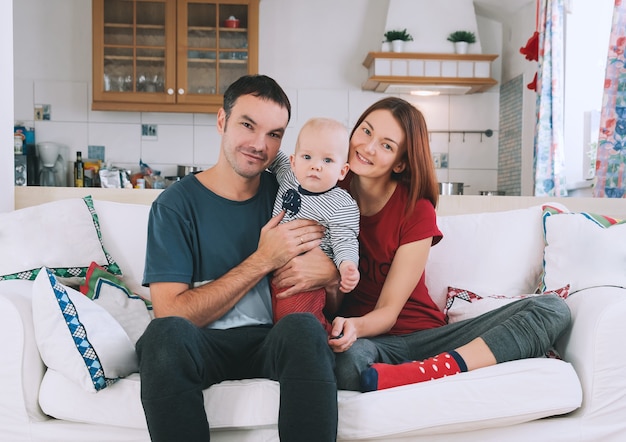 Pais felizes com bebê e cachorro no sofá no interior de casa Conceito de família de estilo de vida