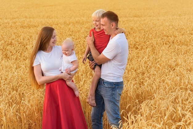 Pais felizes com dois filhos andando pelo campo de trigo Fim de semana com a família fora