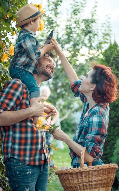 Pais felizes com o seu filho pequeno a beijar-se na natureza em flores