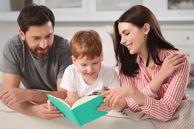 Pais felizes com seu filho lendo livro no sofá em casa