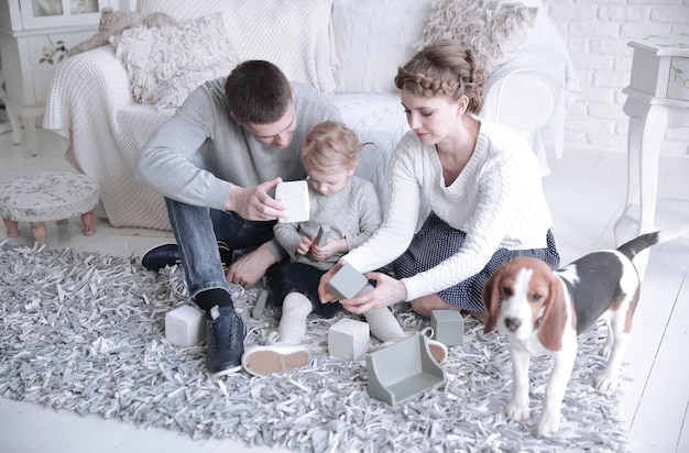 Pais felizes com uma filha e um animal de estimação sentado no sofá.