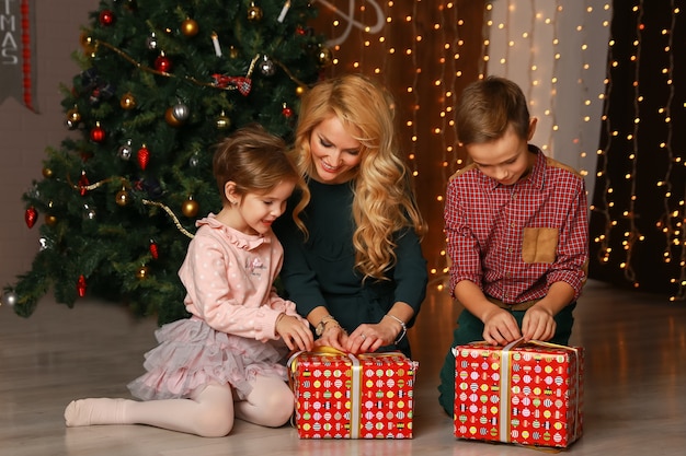 Pais felizes e animados, olhando como filha abrindo o presente de Natal.