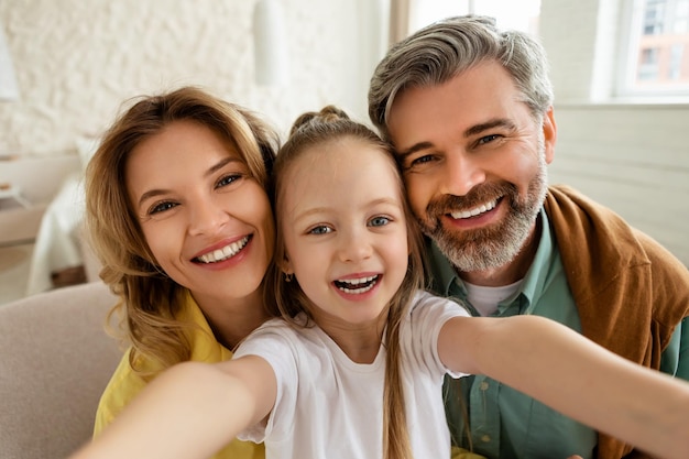 Pais felizes e filha fazendo selfie sorrindo posando em casa