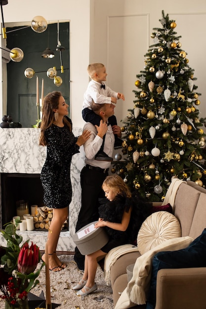 Pais felizes e seus filhos, filha e filho, esperando o Natal em casa e decorando a árvore de Natal Natal em família em casa