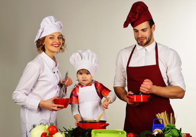 Pais felizes ensinam filho pequeno cozinhando família com filho pequeno preparando comida na cozinha