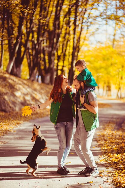 Foto pais felizes se divertem com seu filho pequeno no parque de outono