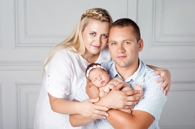 Pais felizes segurando uma linda garota recém-nascida. Mãe, pai e bebê. Fechar-se. Retrato de família sorridente com o recém-nascido nas mãos. Conceito de família feliz