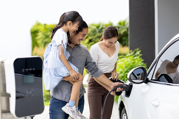 Pais jovens progressistas e filha morando em uma casa com carro elétrico