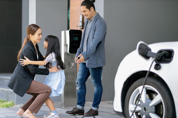 Pais jovens progressistas e filha morando em uma casa com carro elétrico